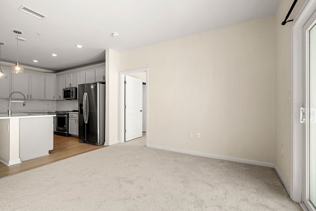 2 Stratton Drive, Unit 102 Woburn, MA 01801 - Photo 5 of 32 a view of a kitchen with refrigerator and white cabinets