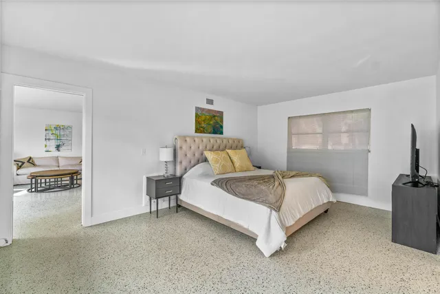 a spacious bedroom with a bed and a flat screen tv