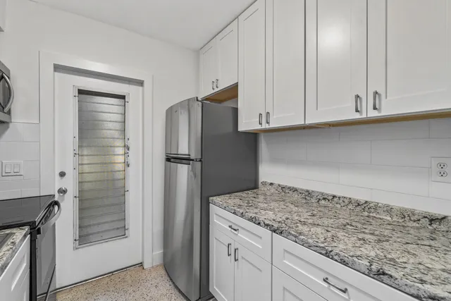 a kitchen with granite countertop white cabinets and refrigerator