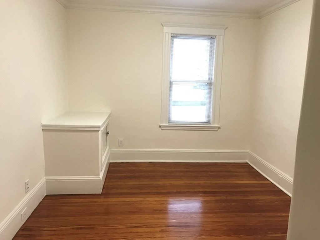 65 Conwell Avenue, Unit 1 Somerville, MA 02144 - Photo 11 of 16 an empty room with wooden floor and windows