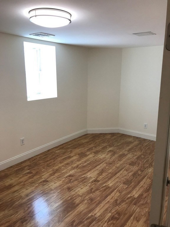 65 Conwell Avenue, Unit 1 Somerville, MA 02144 - Photo 14 of 16 an empty room with wooden floor and windows