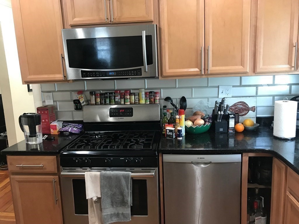 65 Conwell Avenue, Unit 1 Somerville, MA 02144 - Photo 6 of 16 a kitchen with stainless steel appliances granite countertop a stove and a microwave