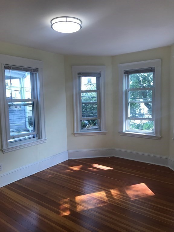 65 Conwell Avenue, Unit 1 Somerville, MA 02144 - Photo 8 of 16 a view of an empty room with wooden floor and a window