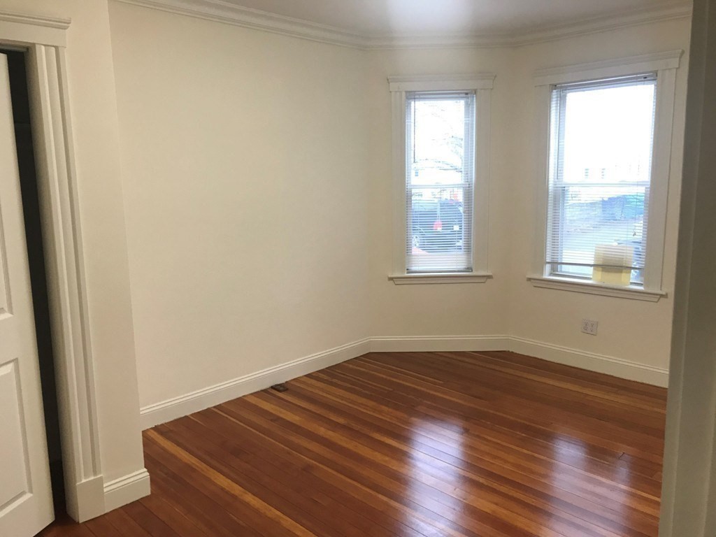 65 Conwell Avenue, Unit 1 Somerville, MA 02144 - Photo 9 of 16 an empty room with wooden floor and windows