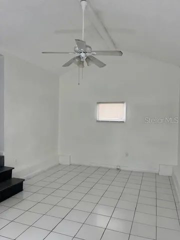 an empty room with a ceiling fan and window