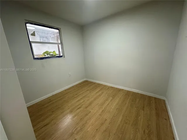 an empty room with wooden floor and a bathroom