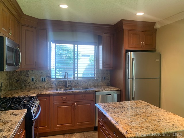 27 Canterbury Lane, Unit 27 Avon, CT 06001 - Photo 3 of 17 a kitchen with kitchen island granite countertop wooden cabinets a sink a stove a refrigerator and island