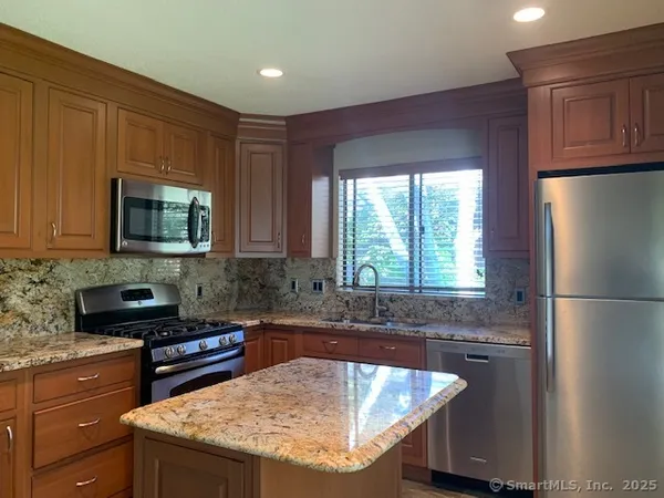 a kitchen with granite countertop a sink stove and refrigerator
