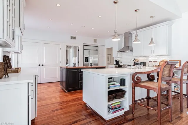 a kitchen with stainless steel appliances granite countertop a stove a sink a refrigerator and a dining table with wooden floor