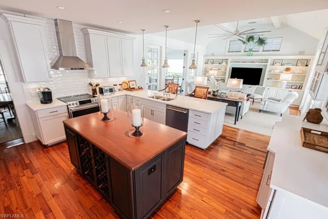 a open kitchen with stainless steel appliances granite countertop a stove top oven a sink dishwasher and a fireplace with wooden floor