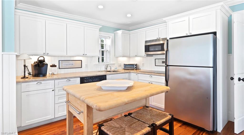 187 Broad Avenue South Naples, FL 34102 - Photo 24 of 33 Kitchen with ornamental molding, stainless steel appliances, white cabinets, light wood-type flooring, and light stone countertops