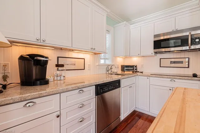 a kitchen with granite countertop white cabinets and stainless steel appliances