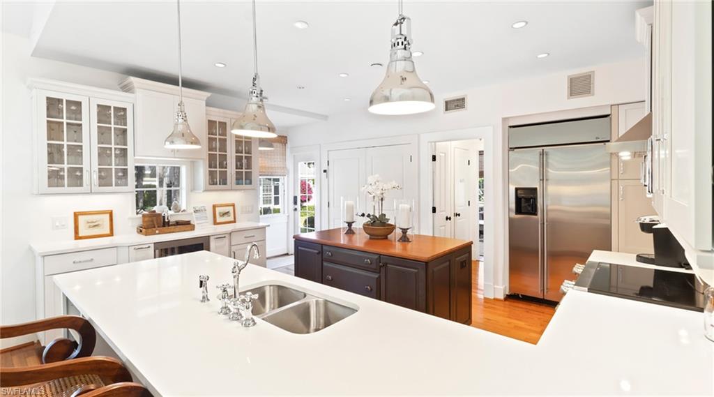 187 Broad Avenue South Naples, FL 34102 - Photo 7 of 33 Kitchen with a kitchen island, glass insert cabinets, stainless steel built in refrigerator, a breakfast bar area, and hanging light fixtures