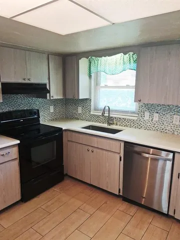 a kitchen with granite countertop cabinets stainless steel appliances a sink and a window