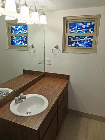 a bathroom with a sink a mirror and a picture on the wall