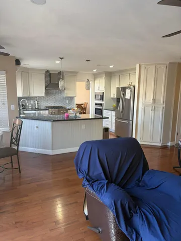 a living room with stainless steel appliances furniture and a wooden floor