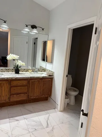 a bathroom with a granite countertop sink toilet and mirror