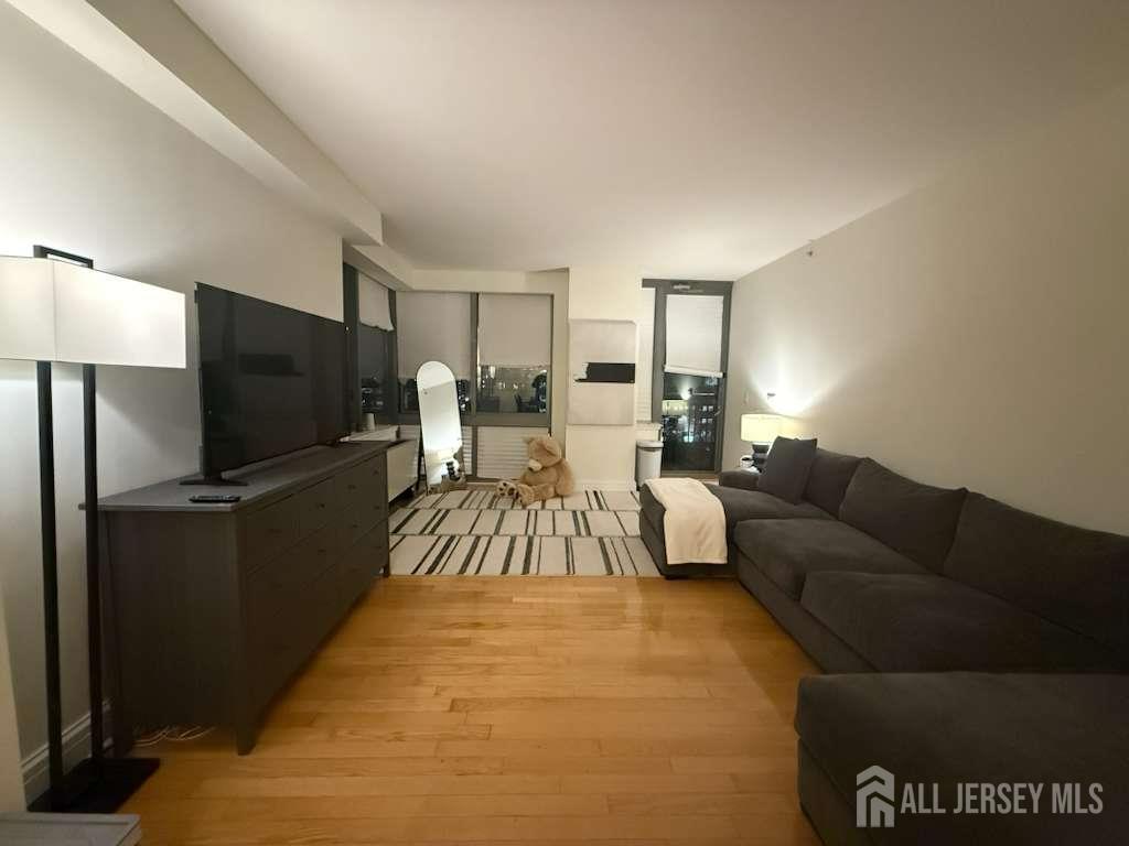 1 Spring Street, Unit 702 New Brunswick, NJ 08901 - Photo 2 of 10 a living room with a couch and a flat screen tv