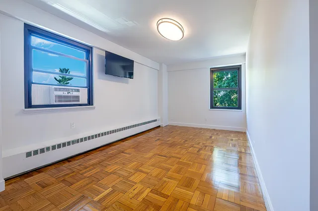a view of an empty room with a window and wooden floor