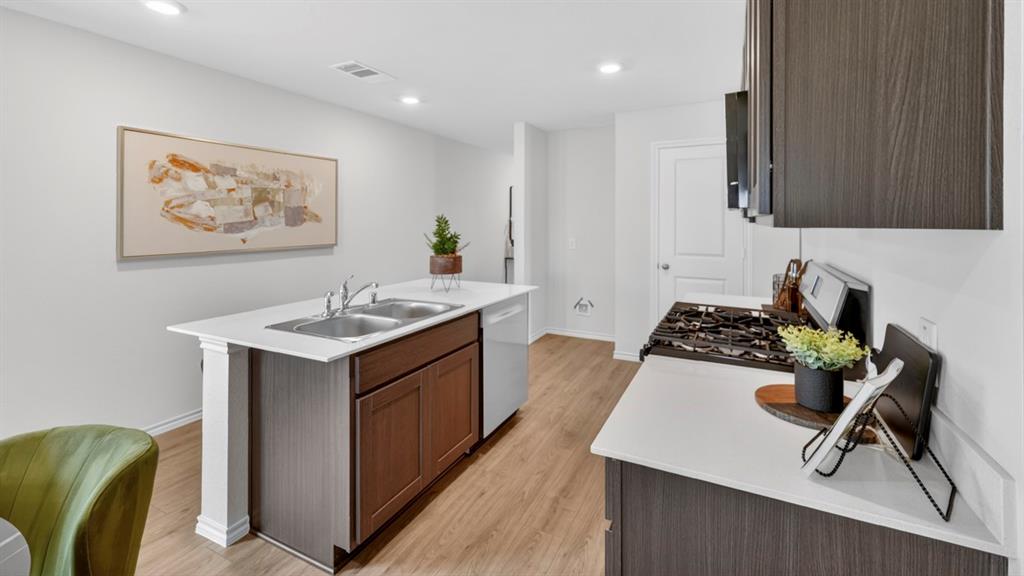 3514 Spring Time Street Terrell, TX 75126 - Photo 5 of 26 Open-concept kitchen featuring an island with a double basin stainless steel sink, wood-finish flooring, recessed lighting, white countertops, and dark wood-finish cabinetry