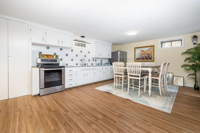 a living room with stainless steel appliances furniture a large window and wooden floor