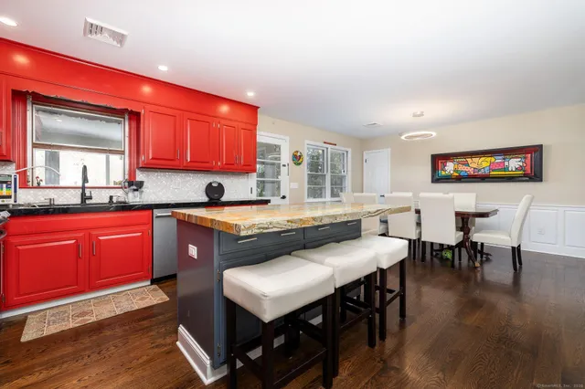 a kitchen with stainless steel appliances granite countertop a stove a sink dishwasher a dining table and chairs with wooden floor