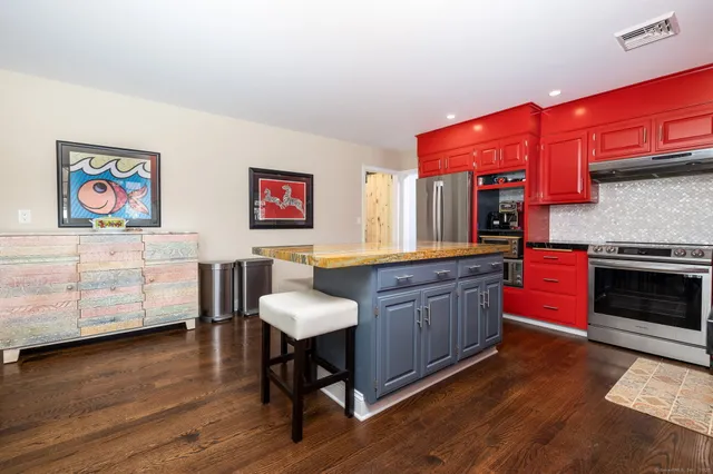 a kitchen with stainless steel appliances granite countertop a kitchen island a stove a sink a dining table and chairs with wooden floor