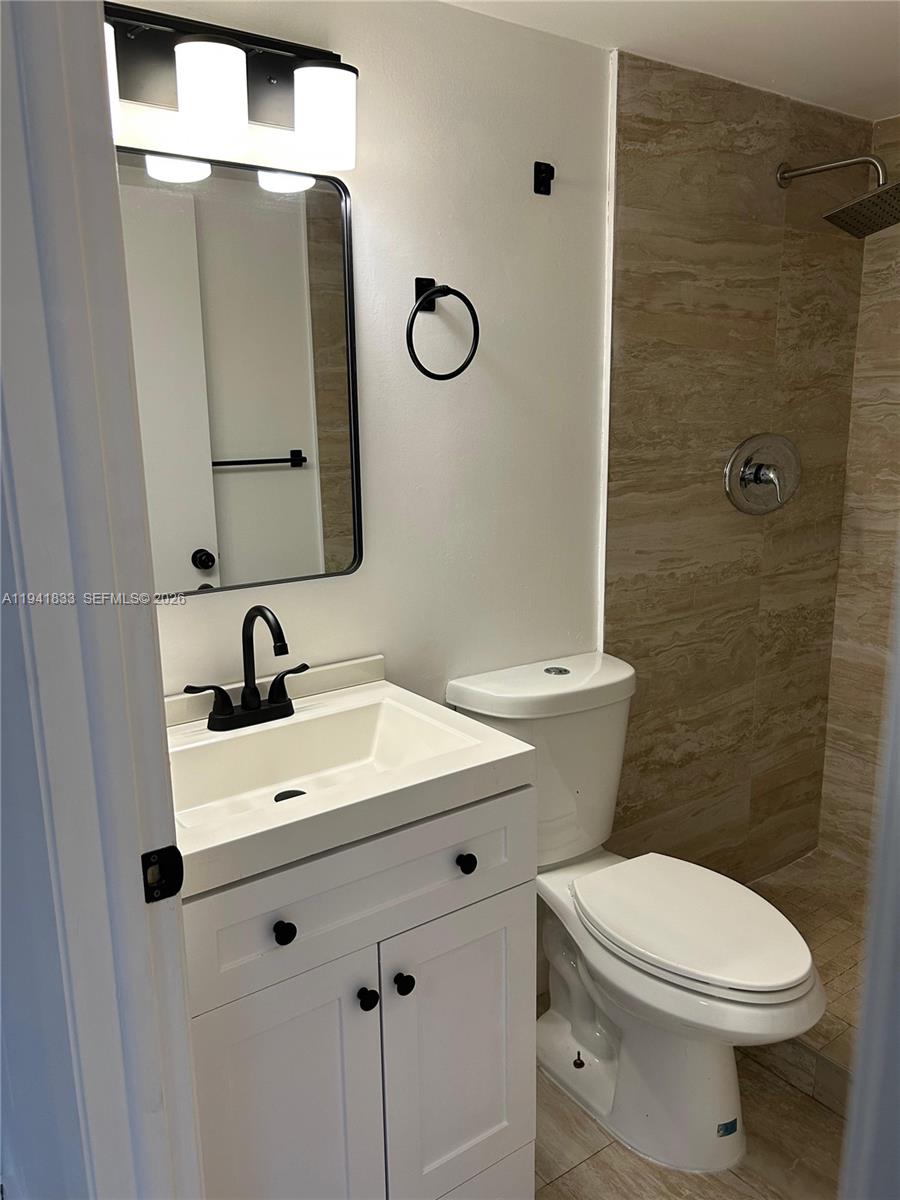 10027 Winding Lake Road, Unit 103 Sunrise, FL 33351 - Photo 9 of 11 a bathroom with a toilet sink and mirror