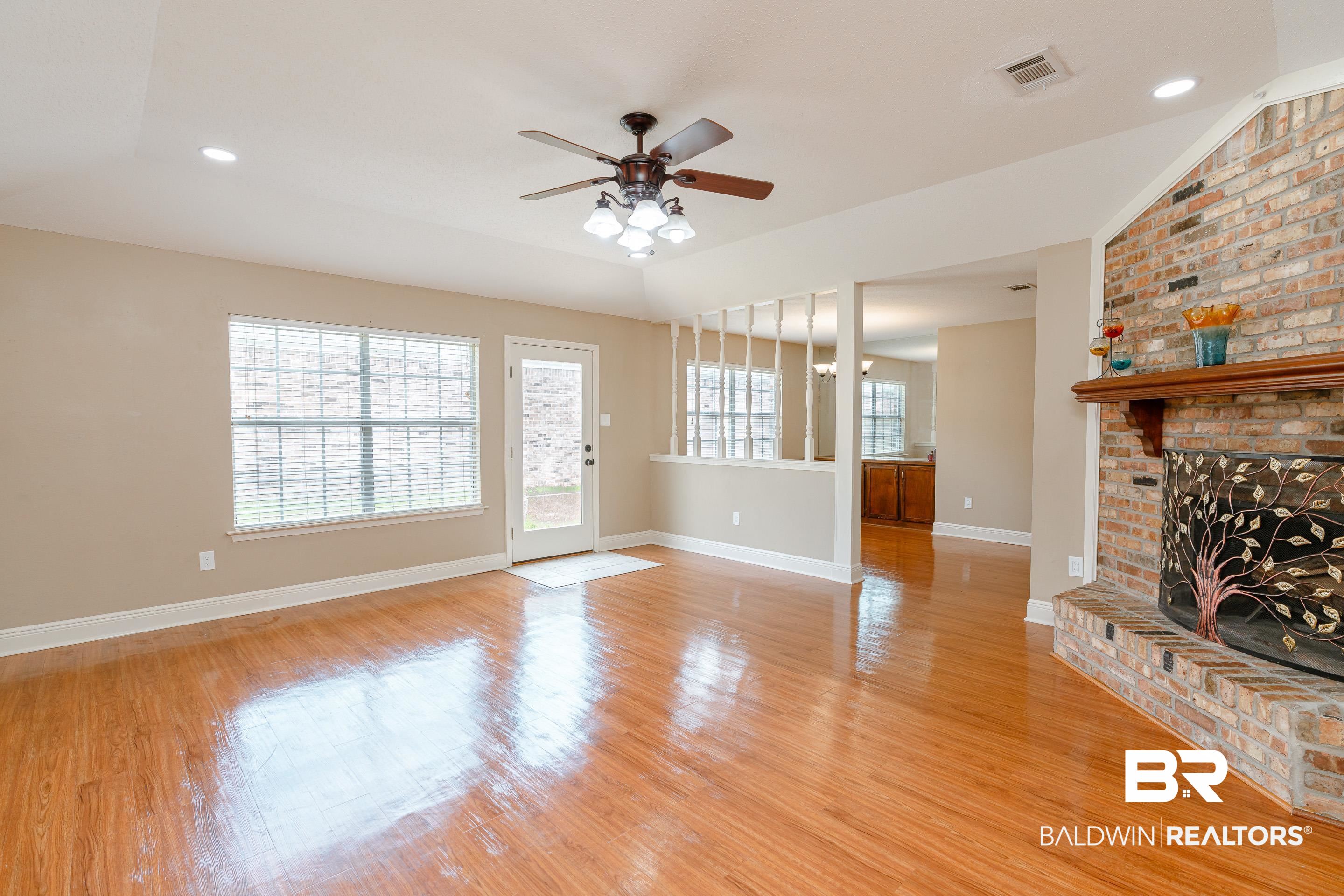 23 Old Mill Court Mobile, AL 36608 - Photo 7 of 37 Unfurnished living room with a brick fireplace, ceiling fan, light wood-type flooring, and plenty of natural light