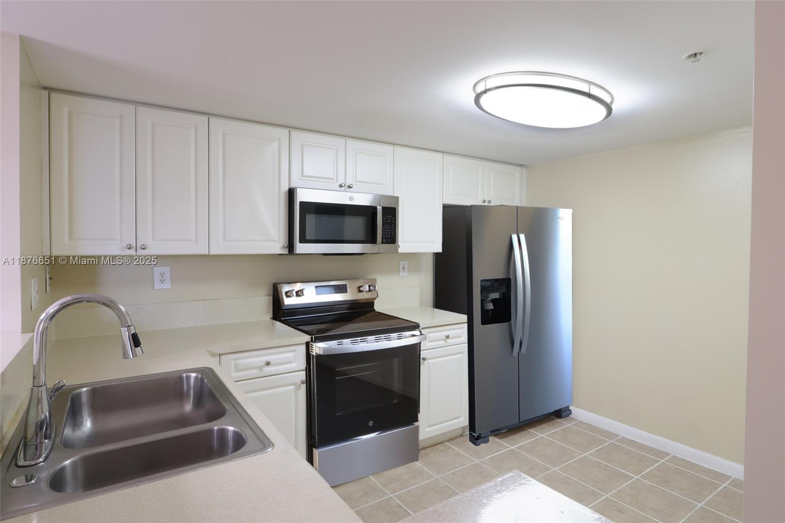 a kitchen with stainless steel appliances a sink a stove a microwave a sink a refrigerator and cabinets