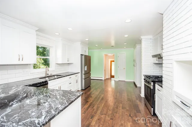 a large kitchen with stainless steel appliances granite countertop a lot of counter space and wooden floors