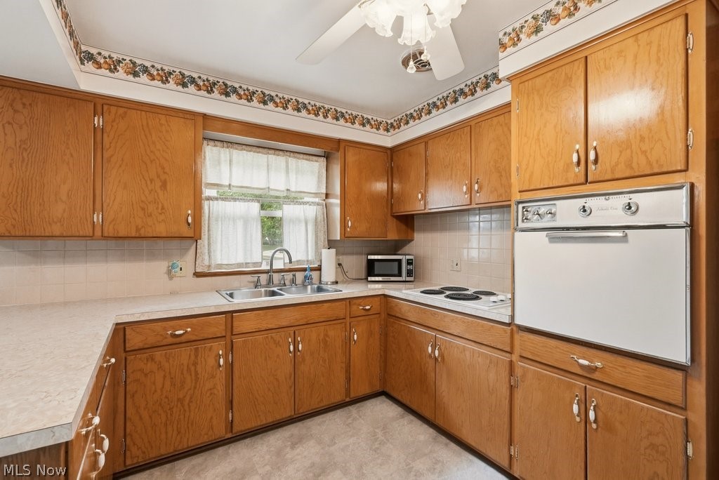161 Pinehurst Road Munroe Falls, OH 44262 - Photo 14 of 40 Kitchen featuring extensive wood cabinetry, L-shaped countertops, a double basin sink beneath a window, a built-in wall oven, and a separate electric cooktop