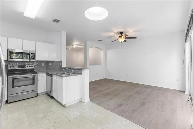 a view of a kitchen with a sink a stove top oven and cabinets