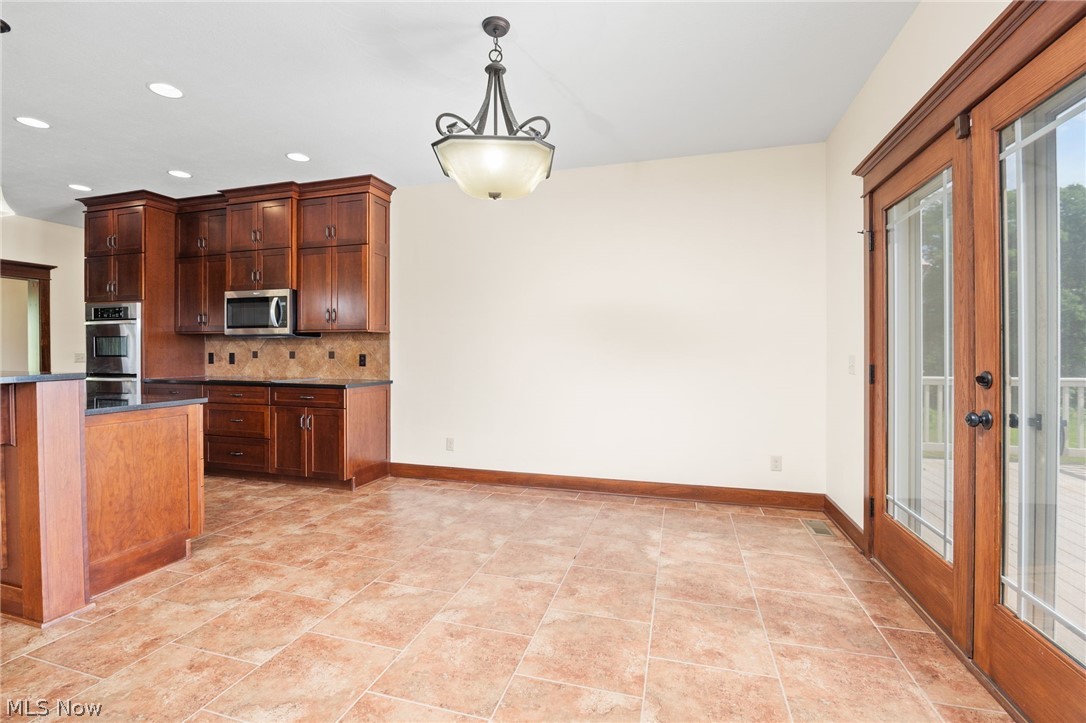 6925 River Styx Road Medina, OH 44256 - Photo 8 of 49 Kitchen and dining area featuring warm wood cabinetry, a built-in oven and microwave, dark countertops, and a decorative tile backsplash