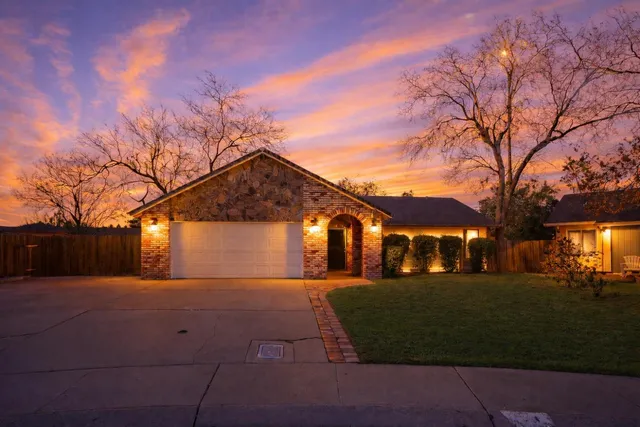 a front view of a building with a yard and trees