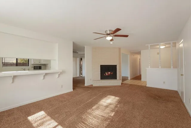 a view of an empty room with a fireplace and a chandelier fan