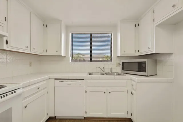 a kitchen with cabinets appliances a sink and a window