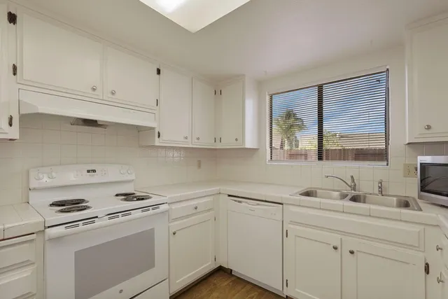 a kitchen with white cabinets and white appliances