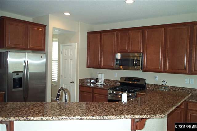 598 Little Sorrel Court Reno, NV 89521 - Photo 4 of 7 a kitchen with kitchen island granite countertop a sink dishwasher stove and cabinets with wooden floor