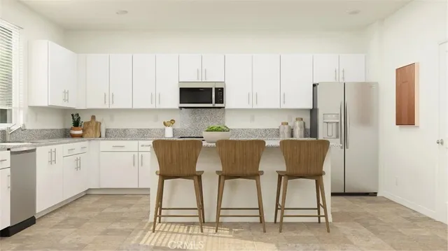 a kitchen with stainless steel appliances granite countertop a table chairs microwave and sink