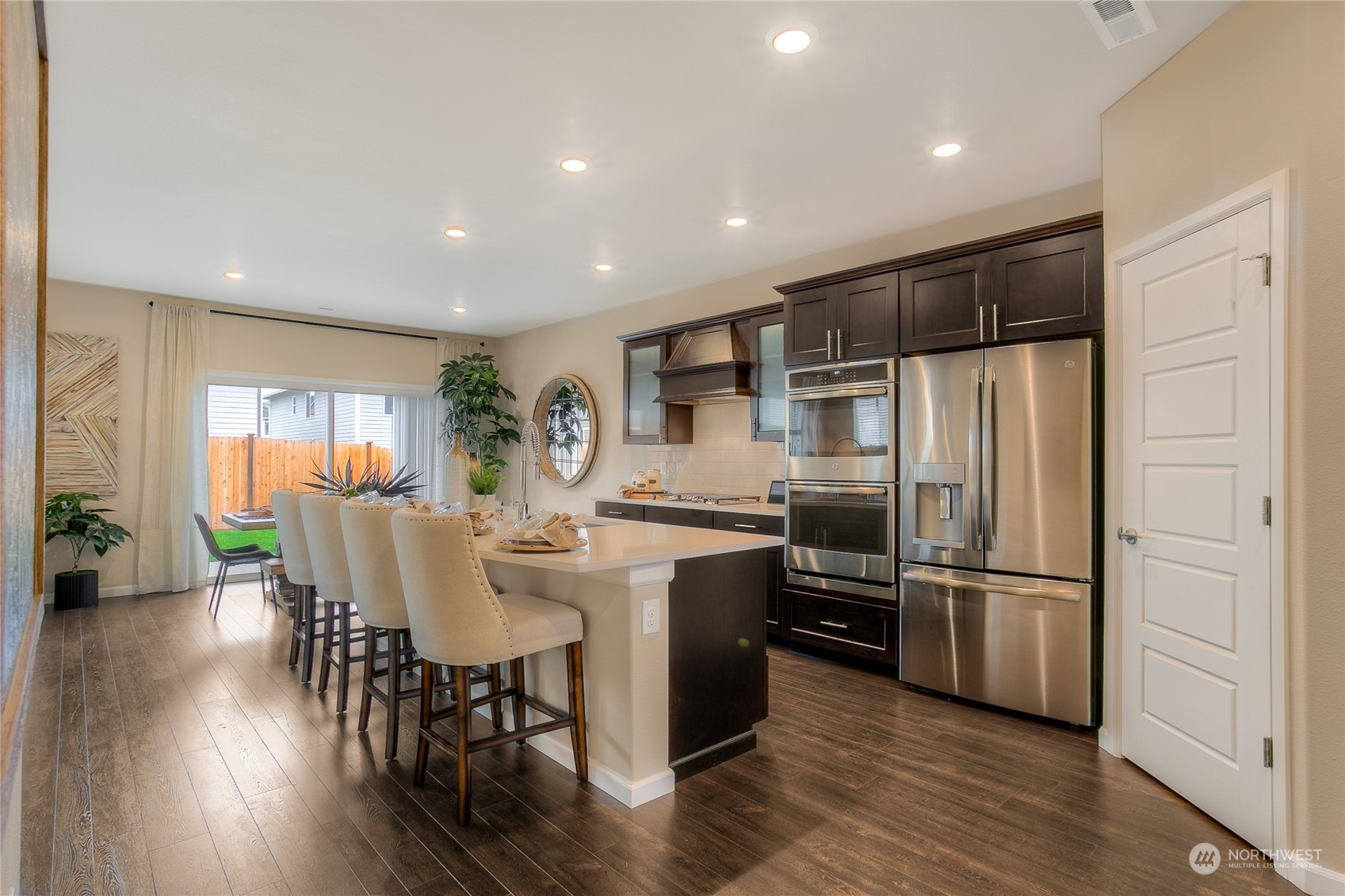 20828 42nd Drive Southeast, Unit 145 Bothell, WA 98021 - Photo 6 of 15 a kitchen with stainless steel appliances a refrigerator a stove a dining table and chairs with wooden floor