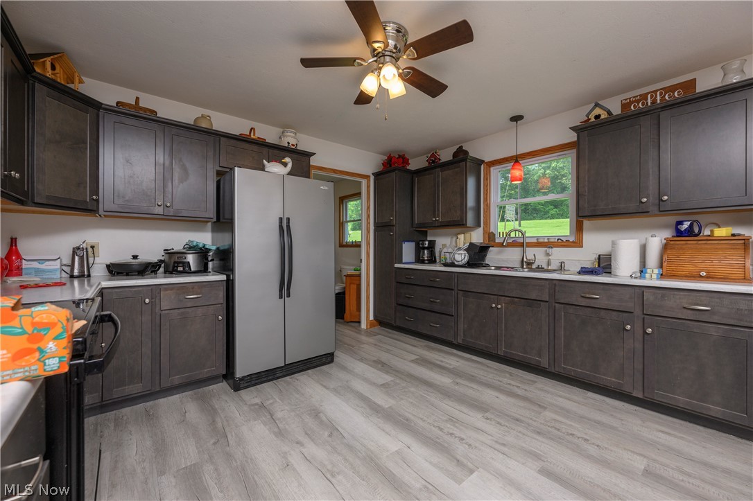 9427 Stonecreek Road Southwest Newcomerstown, OH 43832 - Photo 18 of 29 Kitchen featuring wood-finish flooring and dark wood cabinetry with brushed nickel hardware
