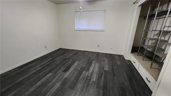 an empty room with wooden floor closet and windows