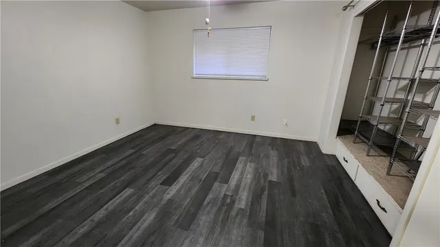 an empty room with wooden floor closet and windows