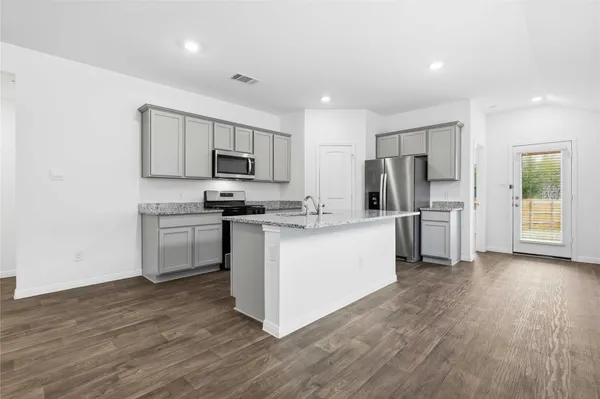 a kitchen with granite countertop a refrigerator stove top oven and sink
