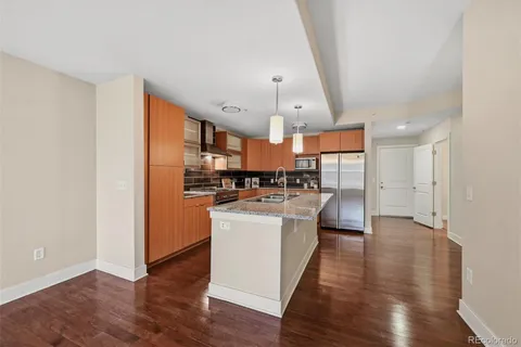 a kitchen with stainless steel appliances a refrigerator a sink dishwasher a stove and white cabinets with wooden floor