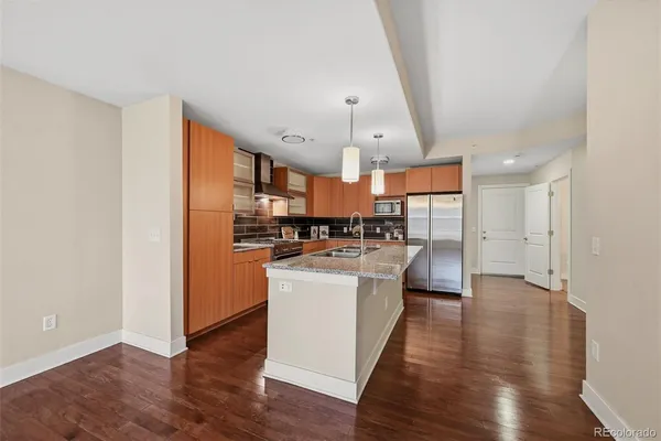 a kitchen with stainless steel appliances a refrigerator a sink dishwasher a stove and white cabinets with wooden floor