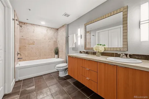 a bathroom with a double vanity sink toilet mirror and bathtub