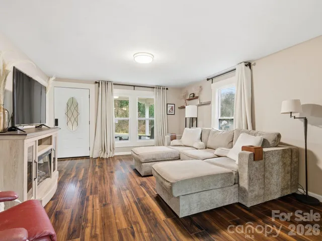 a living room with furniture a flat screen tv and a wooden floor