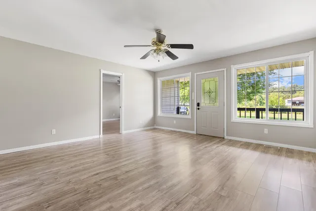 a view of a livingroom with wooden floor ceiling fan and windows